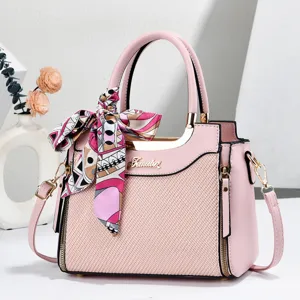 Detail shot of pink tote handbag featuring elegant printed silk scarf accessory and hardware.