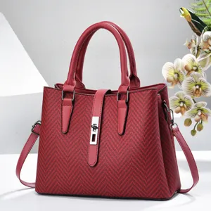 Red structured tote bag detail, featuring textured chevron pattern and secure metal lock closure.