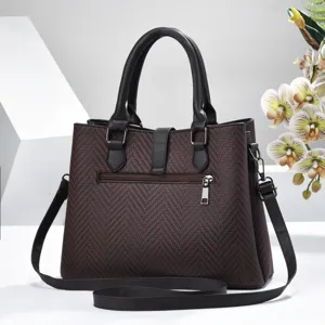 Close-up detail of the dark brown woven shoulder handbag with elegant lock and strap.