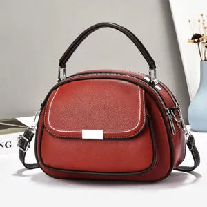 Nahaufnahme der roten Handtasche aus Kieselleder mit weißen Nähten und Silberbeschlägen