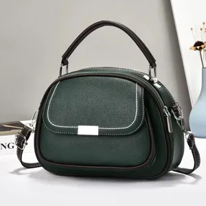 Detailansicht einer grünen Handtasche mit Doppeltaschen, Strukturleder und Tragegriff.