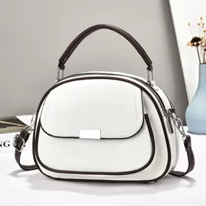 Detailansicht einer eleganten weißen Handtasche mit braunem Rand und Silberschnalle.