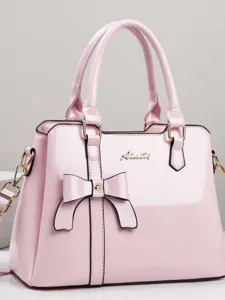 Elegant pink patent leather handbag featuring a stylish bow decoration and top handles