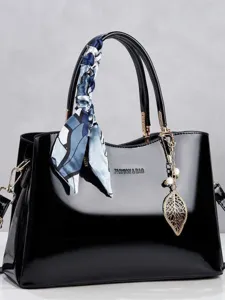 Elegant black patent leather handbag with silk scarf and gold leaf charm accessory