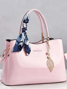 Elegant pink patent leather handbag with scarf handle detail and stylish gold leaf charm