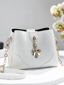 Trendy white leather bucket bag for women with chic gold chain and bow crystal pendant.