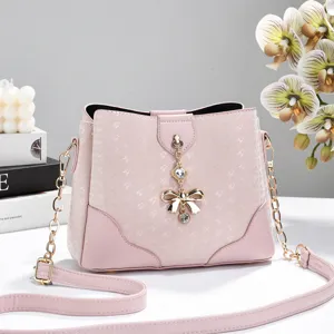 Borsa secchiello rosa con ciondolo fiocco, design stampato e tracolla a catena.