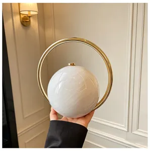 Acryl bolvormige avondtas detail, witte marmer textuur bol met elegante gouden ring handvat.