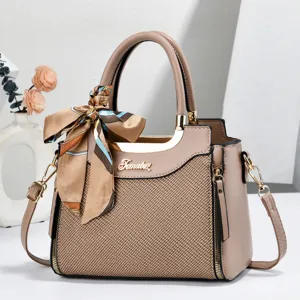 Detailed view of stylish women shoulder handbag with textured fabric, silk scarf, and metal plaque.