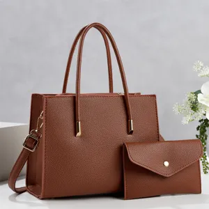 Detail view of brown leather tote bag with matching envelope pouch and double handles.