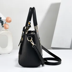 Detail view of a black women's crossbody tote bag with chic silk scarf and metal hardware.