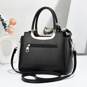 Detailed view of black women's handbag with gold hardware and chic printed twilly scarf accent.