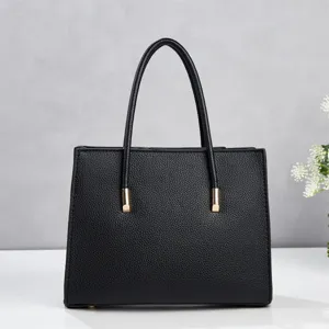 Detailed view of the black PU leather tote bag showing fine texture and golden metal hardware.