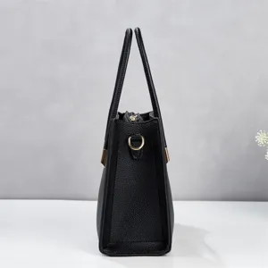 Side detail view of black textured leather tote bag with metal hardware and spacious design.