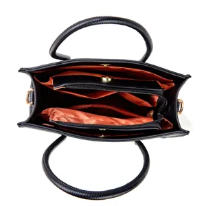 Interior detail view of black PU leather tote bag with orange lining and compartments.