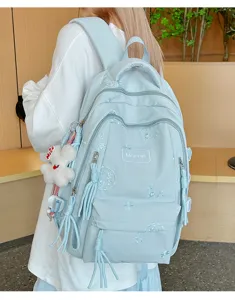 Vista dettagliata dello zaino da studente azzurro con ricamo delicato e ciondolo di peluche.
