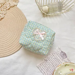Close-up detail of the quilted cosmetic pouch showing blue yellow plaid and lace bow.