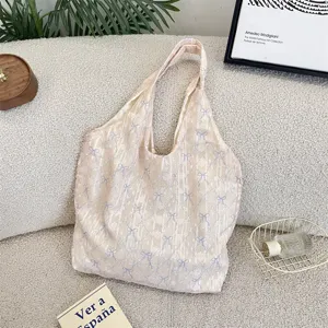 Close-up detail of the bow textured canvas shoulder bag in soft cream color aesthetic.