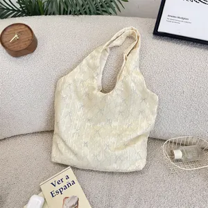 Cream fabric shoulder bag with bow pattern, casual tote detail showing texture and design.