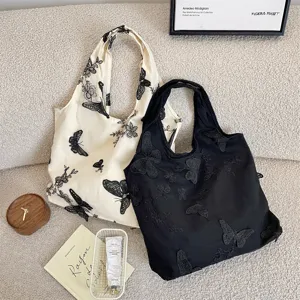 Vue détaillée de sacs cabas en toile avec de délicates broderies de dentelle papillon.