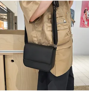 Dettaglio della borsa a tracolla in pelle PU nera, design compatto con tracolla regolabile.