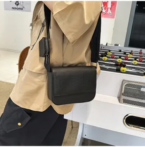 Dettaglio della borsa a tracolla nera in PU, con patta testurizzata e mini pochette.