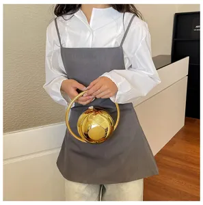 Gouden ronde bal handtas met metalen ringhandvat, stijlvolle unieke avondtas detail.