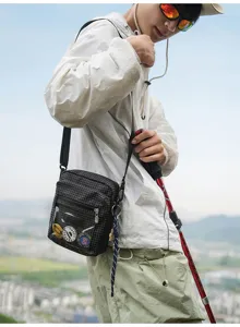 Nahaufnahme der schwarzen Karo-Nylorumhängetasche mit transparenter Vordertasche.