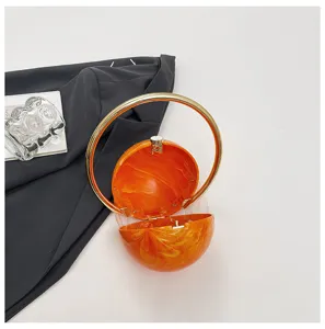 Oranje acryl bol avondtas detailweergave met marmertextuur en gouden ringhandvat.