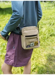 Nylon Umhaengetasche mit klarem Fenster und coolen Ansteckern fuer den taeglichen Einsatz.