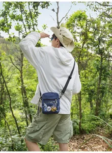 Detailaufnahme einer blauen Karomuster Nylon Umhängetasche mit transparenter Vordertasche.