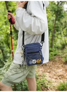 Detailansicht der blauen karo Nylon Umhängetasche mit transparenter Tasche und coolen Pins.
