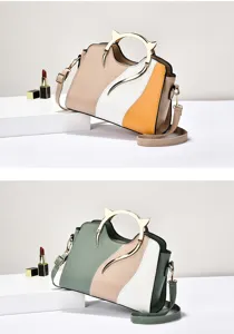 Detail view of stylish color-block women handbag with unique metal cat-ear handle and strap.