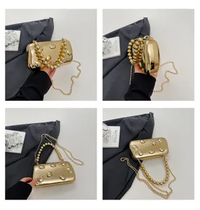 Detailansicht einer glamourösen metallisch goldenen Abendtasche mit Perlenhenkel.