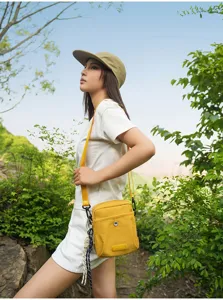 Outdoor detail shot showcasing the compact yellow crossbody bag worn by a model.
