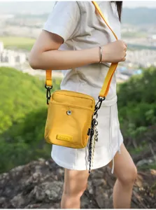 Outdoor yellow canvas cross body bag detail shot, compact design for hiking and travel.