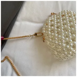 Detalle bolso perlas, cadena metal dorado y cierre, elegante cartera vista cercana