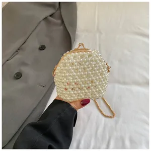 Detalle de mini bolso de perlas con artesanía exquisita y cadena metálica dorada.