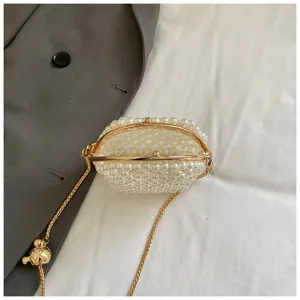 Primer plano detallado del elegante bolso de perlas huecas con cierre de beso y cadena.