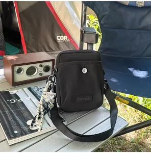 Close-up view of the black tactical crossbody bag showing strap details in outdoor camping scene.