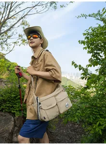 Outdoor hiking scene detail showing the durable nylon crossbody messenger bag worn by a model.