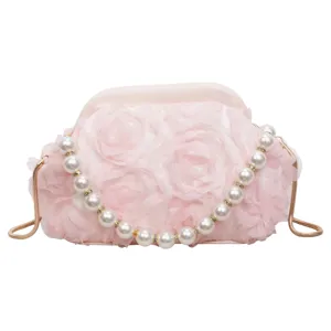 Close-up of pink flower evening bag with pearl handle and delicate metal chain details.
