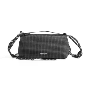 Vista detallada del bolso bandolera negro de rejilla, con tela resistente y correa gruesa.