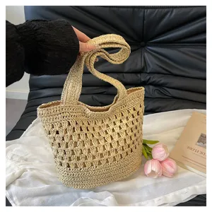Gros plan cabas paille tressée main, texture ajourée, idéal pour les vacances à la plage d'été.