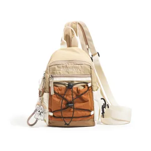 Detail view of colorblock sling bag featuring front zipper pockets, drawstrings, and keychain charm.