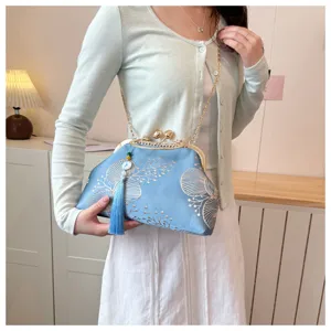 Primo piano della borsa a tracolla ricamata in raso blu con chiusura a bacio e catena oro.
