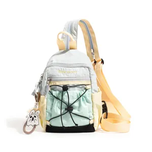 Detailed view of the color-block sling backpack with drawstring front pocket and ghost charm.