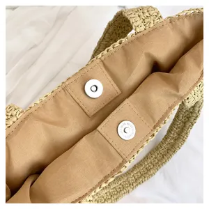 Vue détaillée de la doublure intérieure et du bouton-pression aimanté du sac en paille.