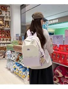 Stylish color-block student backpack with large capacity, cute pendant, and comfortable straps.