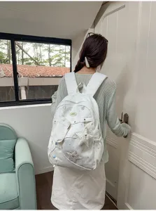 Zaino per studenti bianco con motivi a stelle, simpatici ciondoli in peluche e tasche.
